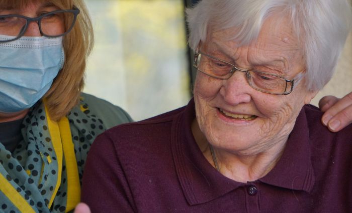 Professional nurse reviewing care plan on tablet/clipboard in home